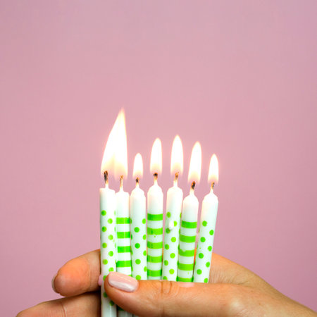 Birthday candles in hand on a pink background with copyspaceの写真素材