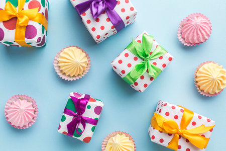 Colorful cupcakes and gift boxes on blue background. Top view.