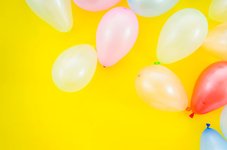 Colorful balloons on yellow background with copy space. Flat lay styleの写真素材