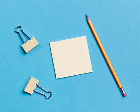 Top view of blank paper sheet and pencil on blue background with copy space