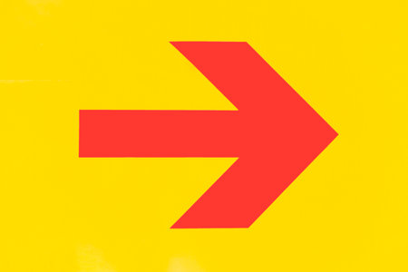 Red arrow sign on yellow background, close-up. Copy space