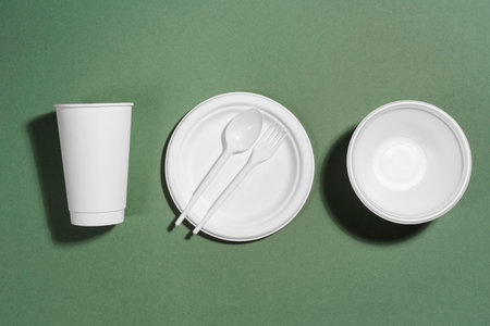 disposable tableware on a green background, top view.の写真素材