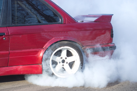 A red  car accelerating with smoke coming from wheelsの写真素材
