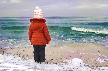 Little girl at the beach looking at the seaの写真素材