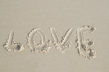 Love  written in soft wet sand on a beachの写真素材