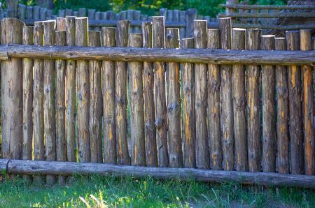 Old wooden fence made of logs in the form of a palisadeの写真素材