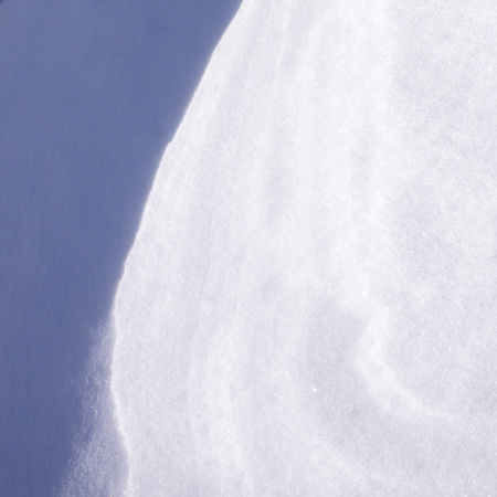 winter snow surface with patterns created by wind and other natural phenomenaの写真素材