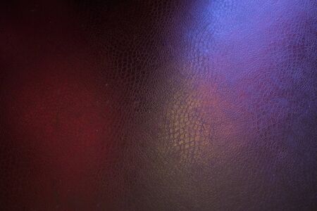the texture of artificial leather is black with dramatic highlights of pink and green shades...