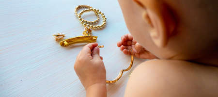 hands of child play with gold jewelry and bijouterie, on white background. concept of womens...
