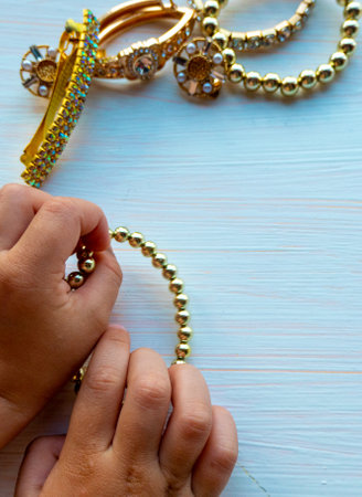 hands of child play with gold jewelry and bijouterie, on white background. concept of womens...
