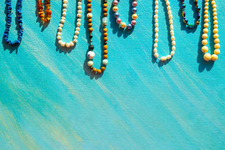 Heap of colored bright jewelry beads on a blue background. Different gems beads necklace. Jewel necklace modern fashion pattern or texture. Space for text. High quality photoの写真素材