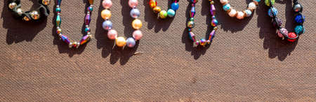 Heap of colored bright jewelry beads on a dark background. Different gems beads necklace. Jewel necklace modern fashion pattern or texture. Space for text. High quality photoの写真素材