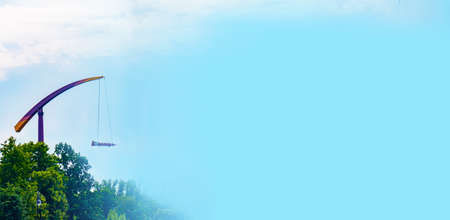 landscape of an amusement park with rocket rides attraction showing above the tree tops against a blue sky. banner with copy spaceの写真素材