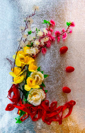 Easter card with painted red Easter eggs and flowers on a silver background. Decorated with painted artificial spring flowers and a scarlet ribbon.の写真素材