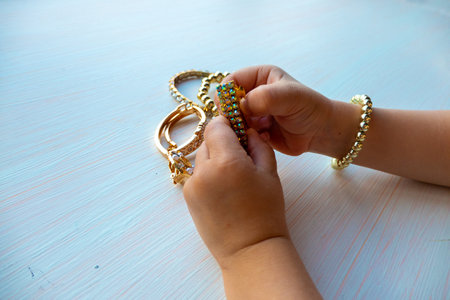 hands of child play with gold jewelry and bijouterie, on white background. concept of womens...