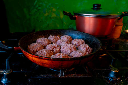 Man hands preparing meatballs with raw mincemeat. Lifestyle close up composition with colorfully kitchen with painted walls. Homemade cooking during lockdown, stay home housekeeping sharing concept. High quality photoの写真素材