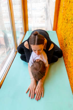 family sports. mother teaches son to do yoga. Helps with stretching. On the balcony In a home apartment.の写真素材
