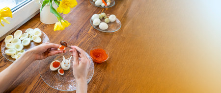 Step by step. egg rabbit figurine for decorationf, for making stuffed eggs. womens hands cut egg in half and fill eggs with red caviar. canapes with red caviar and quail eggs on a plateの写真素材