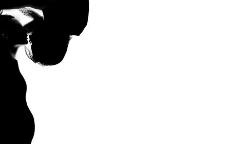 Beautiful pregnant woman and her handsome husband are kissing while spending time together isolated over white background wall. beautiful young couple expecting baby standing together and touching bellyの写真素材