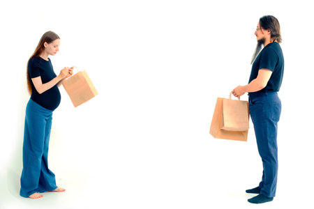 Portrait happy young pregnant woman and her husband with shopping bags and touching her big belly isolated on white background. Pregnancy shopping concept happy young family with shopping bagsの写真素材