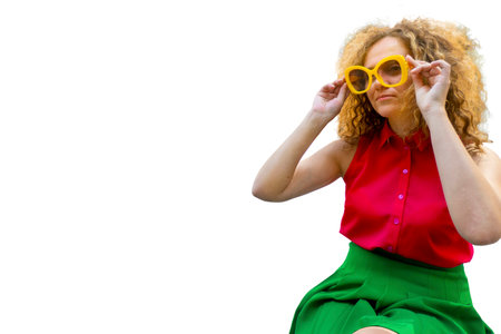 Young blonde woman with long curly hair in red and green fashion closes in sun glasses playful smile happy positive adjusts his glassesの写真素材
