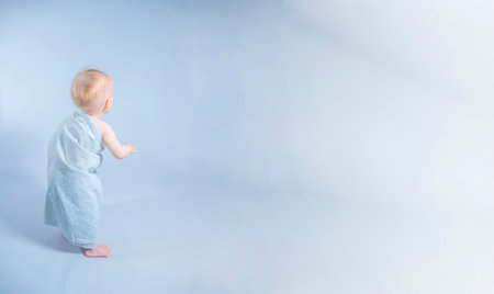 a one-year-old girl in a toga looking up on white background. Banner with copy spaceの写真素材
