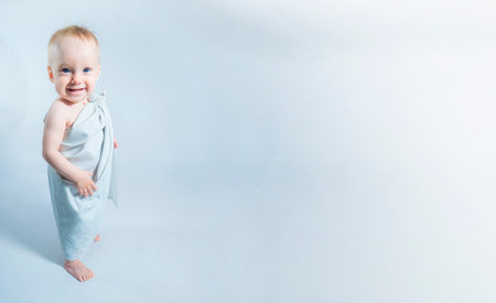 a one-year-old girl in a toga looking up on white background. Banner with copy spaceの写真素材