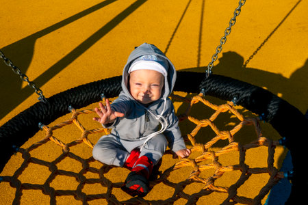 Little baby on swing. Baby girl boy 1 year swinging on a swing in the yard. High quality photoの写真素材