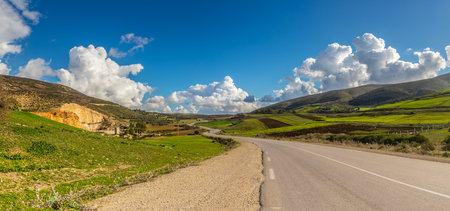 A Scenic Drive Through Mountains and Green Fields Under a Blue Sky with Clouds in Tunisia