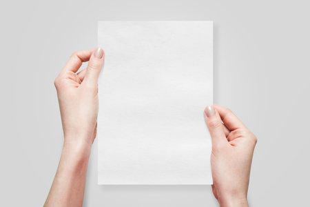 Two Hands Holding an A5 Paper on Gray Backgroundの写真素材