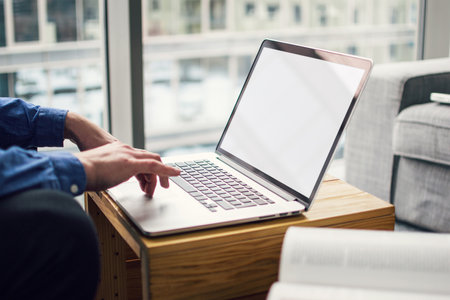 Computer mockup image blank screen with white background for advertising, with hand using laptop contact business search information on desk at coffee shopの写真素材