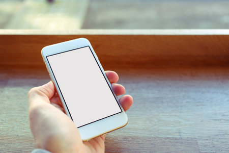 Mobile phone mockup with blank screen on white background for advertising, featuring a handの写真素材