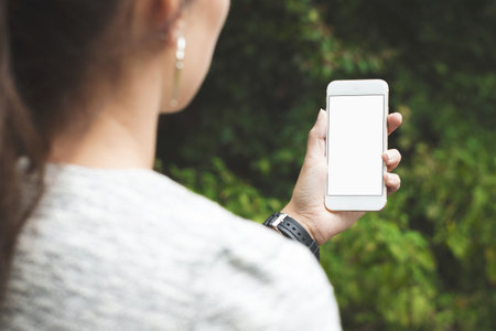 Mobile phone mockup with blank screen on white background for advertising, featuring a hand