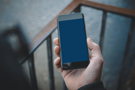 Hand holding a mobile phone mockup with a blank screenの写真素材