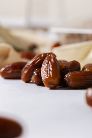 Close-up of fresh organic dates on a white surface with a blurred background, highlighting their...