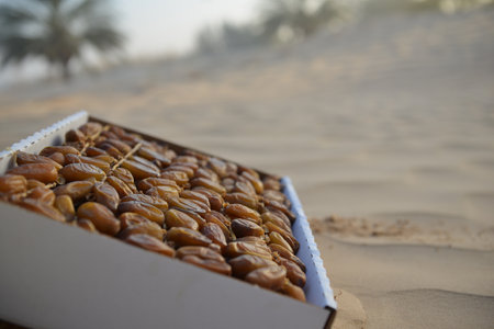 Box of fresh Tunisian dates on desert sand under warm sunlight