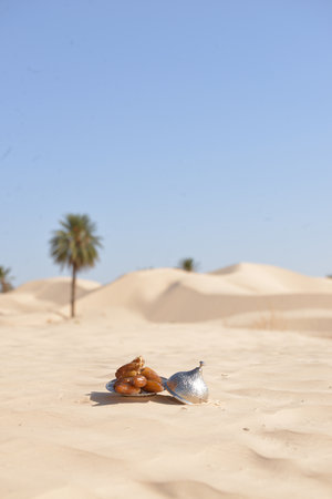 Silver plate of ripe Tunisian dates on golden desert sand with palm treesの写真素材