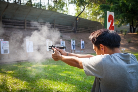 BANGKOK,THAILAND-JANUARY 6: A man testing fire for Glock 19 Gen 4 with firing smoke and ammunition case floating in the air at Ramintra 17 gun field on January 6,2013 in Bangkok,Thailand のeditorial素材