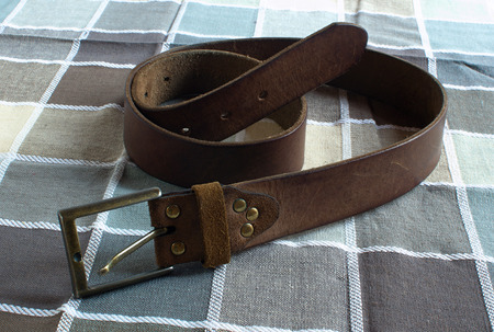 Leather brown belt on checkered fabric backgroundの写真素材