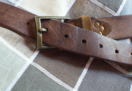 Leather brown belt on checkered fabric backgroundの写真素材