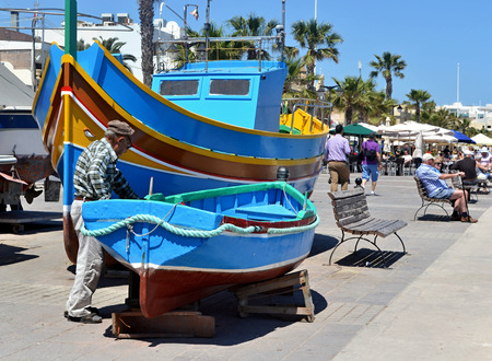 Fisherman checking his boat in luzzu port in Marsaxlokk, Maltaのeditorial素材