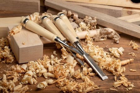Chisel and wooden mallet with wood shavings. Carpenter cabinet maker hand tools on the workbench.