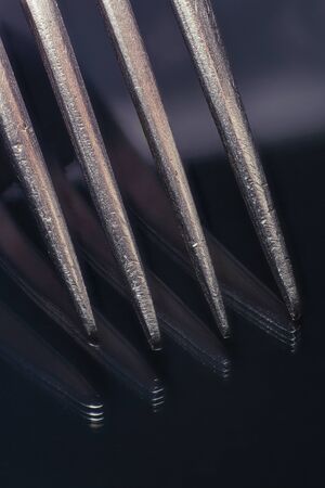 Close-up of a fork with reflection on black glass.