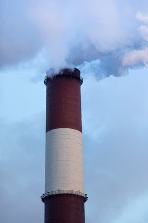 A industrial chimney in the clouds of steam. Sunny winter day.