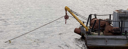 The stern of the boat with a winch lowered into the water. Calm weather on the lake.の写真素材