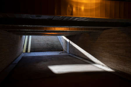 Old underground pedestrian tunnel, crossing the city street highway. Dim tunnel poorly lit by a...
