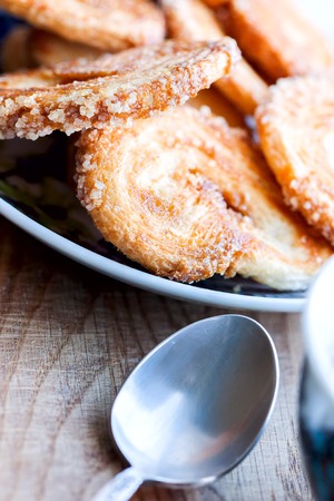 Cookies lies on a saucer close up, near a silver spoon and cup on a wooden backgroundの写真素材