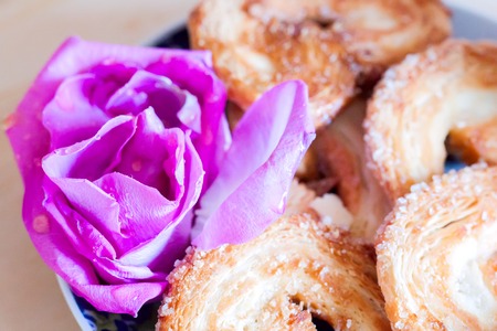 puff pastry close up with rose petals on wooden background
