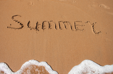 The word summer written in the sand on a beachの写真素材