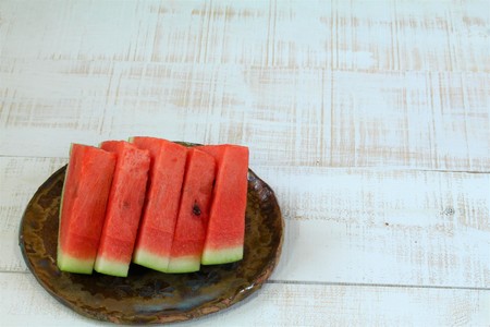 Watermelon slice arranged on a white wooden boardの写真素材